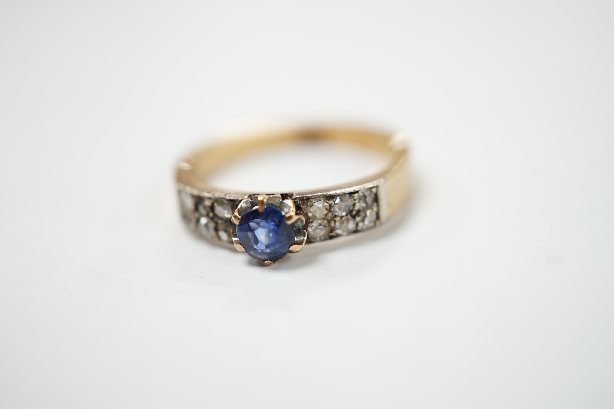 An early 20th century yellow metal (stamped 18) and single stone sapphire set ring, with twelve stone diamond chip set shoulders, size M, gross weight 3.2 grams. Condition - fair